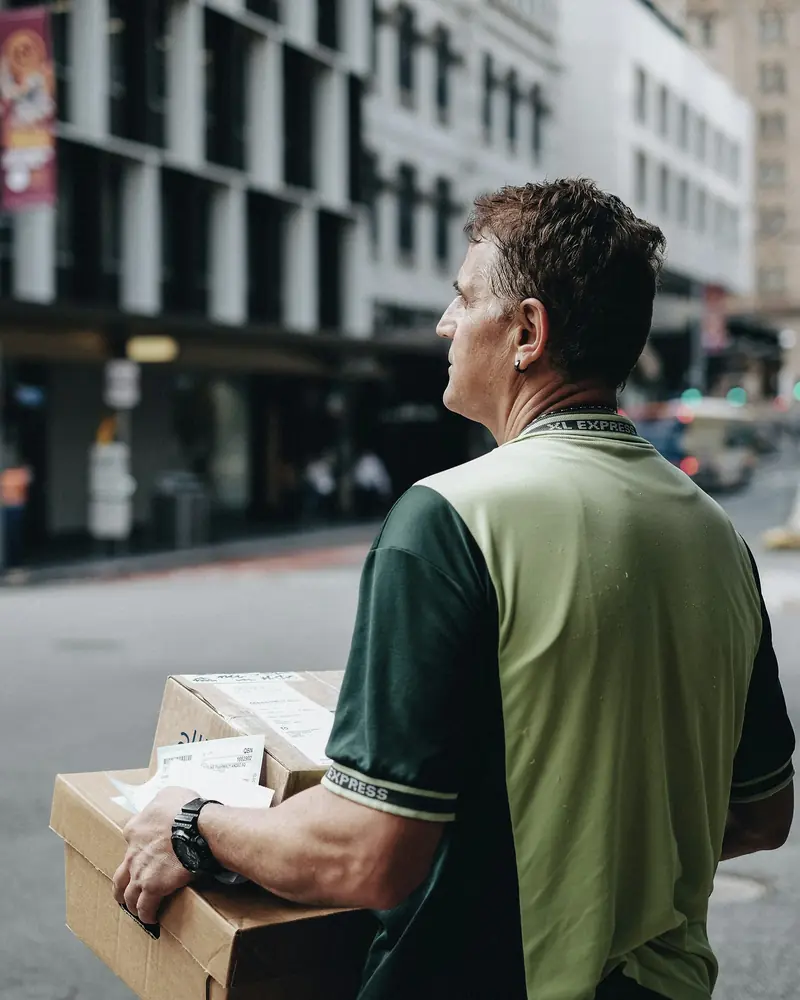 A delivery driver carrying parcels along a city street